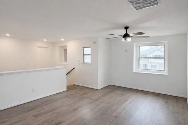 a view of an empty room with wooden floor and a window