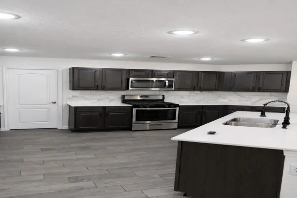 a kitchen with stainless steel appliances a sink a stove top oven a refrigerator and cabinets