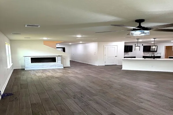 a view of empty room with wooden floor and ceiling fan