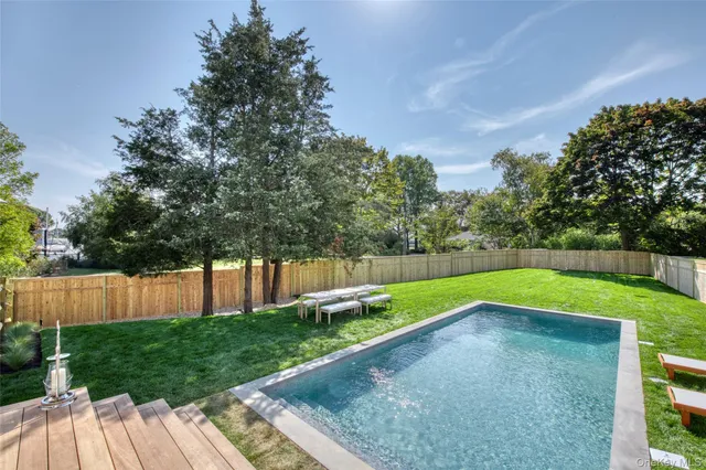 a view of a backyard with large trees and wooden fence