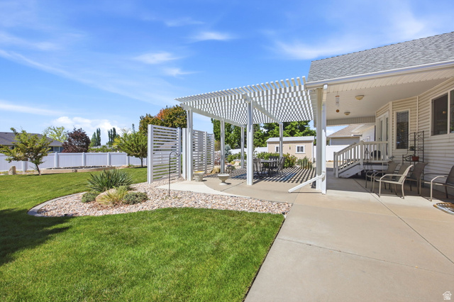 776 Flint Street Layton, UT 84041 - Photo 25 of 41 Expansive backyard with a manicured lawn, a large concrete patio, and a white slatted pergola