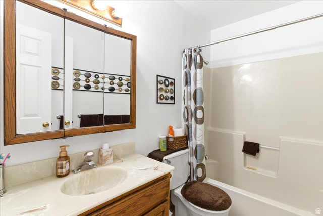 5321 South 3100th Street West Roy, UT 84067 - Photo 53 of 64 Bathroom featuring a wood-finish vanity with an integrated sink and light-toned countertop, a three-panel mirrored medicine cabinet, and a shower/tub combination with a white surround