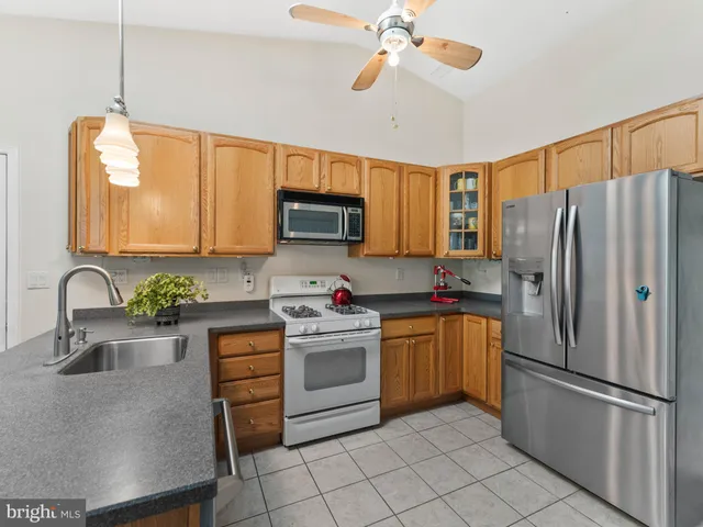 a kitchen with stainless steel appliances granite countertop a refrigerator a stove a sink dishwasher and a microwave