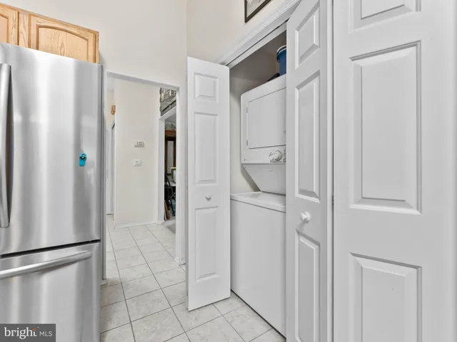 a view of a refrigerator in kitchen and an empty room with wooden floor