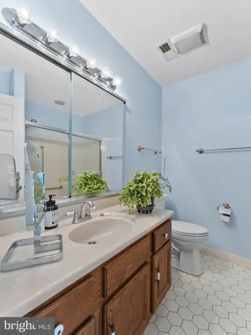 a bathroom with a granite countertop sink a large mirror and a toilet