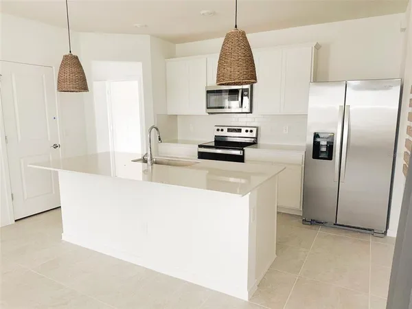 a kitchen with stainless steel appliances a refrigerator sink and white cabinets