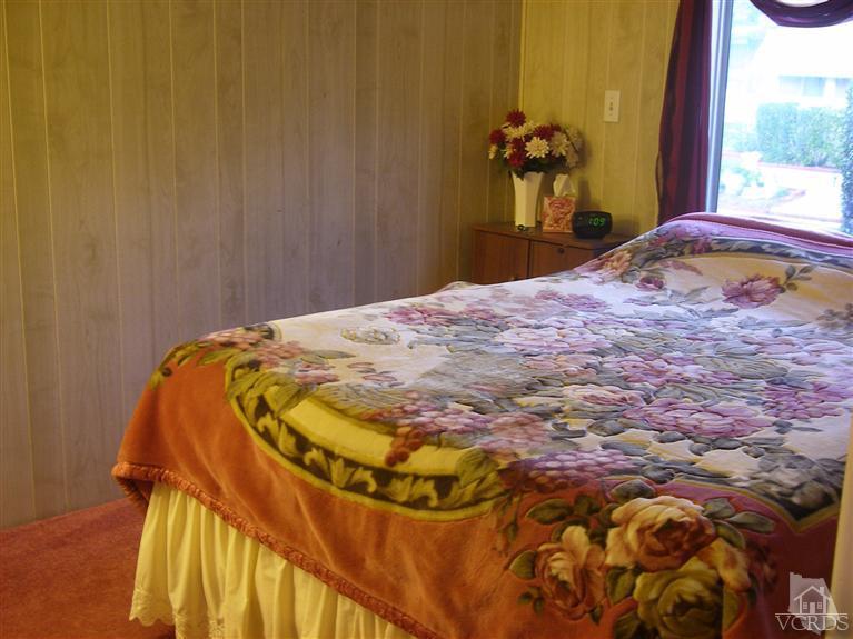 6480 Katherine Road, Unit 126 Simi Valley, CA 93063 - Photo 14 of 18 a bedroom with a bed and a chandelier