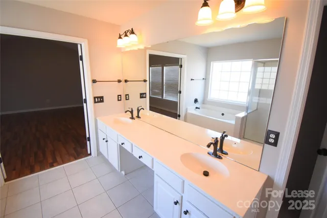 a spacious bathroom with a double vanity sink a mirror and shower