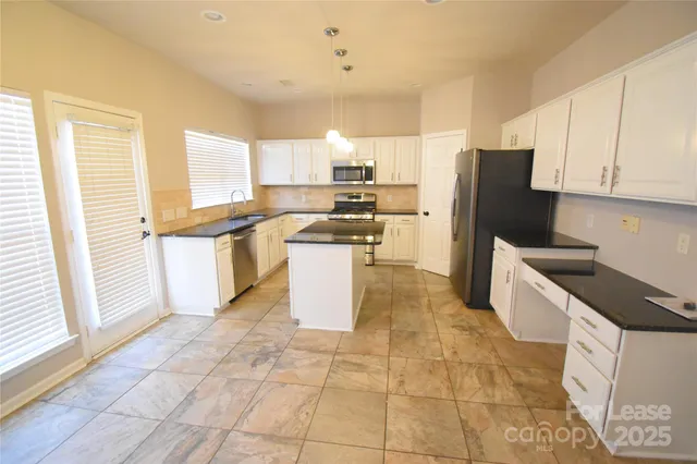 a kitchen with stainless steel appliances granite countertop a stove a sink a microwave and a refrigerator