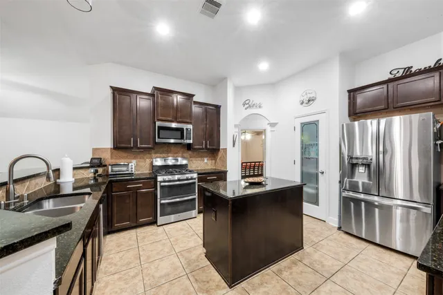 a kitchen with stainless steel appliances granite countertop a refrigerator stove microwave and sink