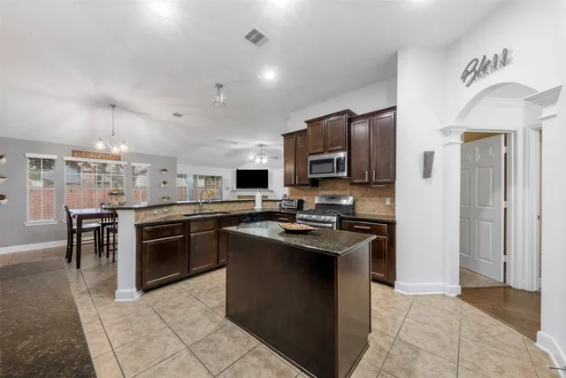 a kitchen with stainless steel appliances granite countertop a stove top oven a sink dishwasher a dining table and chairs