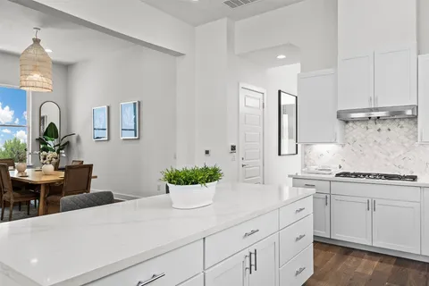 a kitchen with stainless steel appliances kitchen island granite countertop a sink a stove and white cabinets