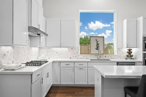 a kitchen with granite countertop a sink a stove and cabinets