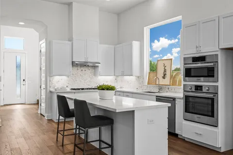 a kitchen with stainless steel appliances a stove a sink refrigerator and a white cabinets