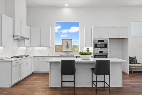 a kitchen with stainless steel appliances granite countertop a table chairs sink and cabinets
