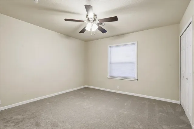 an empty room with a window and a ceiling fan
