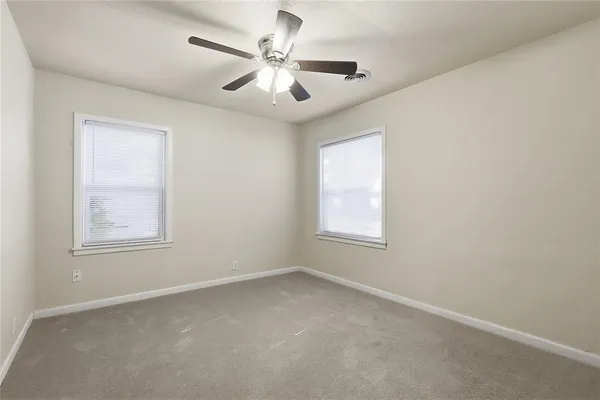 an empty room with windows and fan