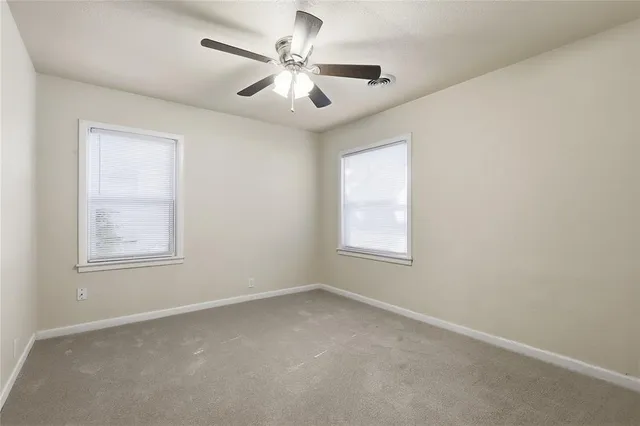 an empty room with windows and fan