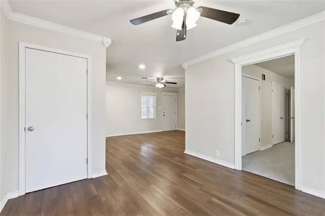 an empty room with wooden floor and a ceiling fan