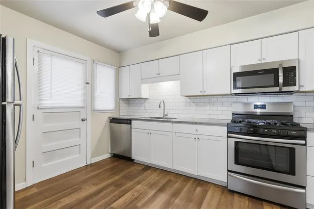 a kitchen with granite countertop white cabinets and stainless steel appliances