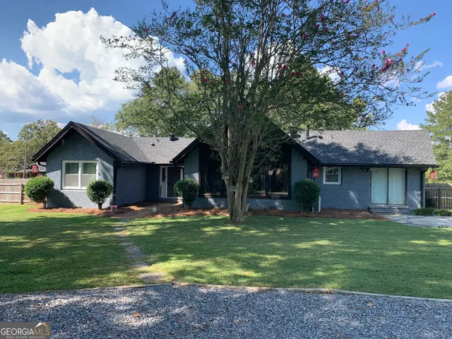 a front view of a house with a garden and trees