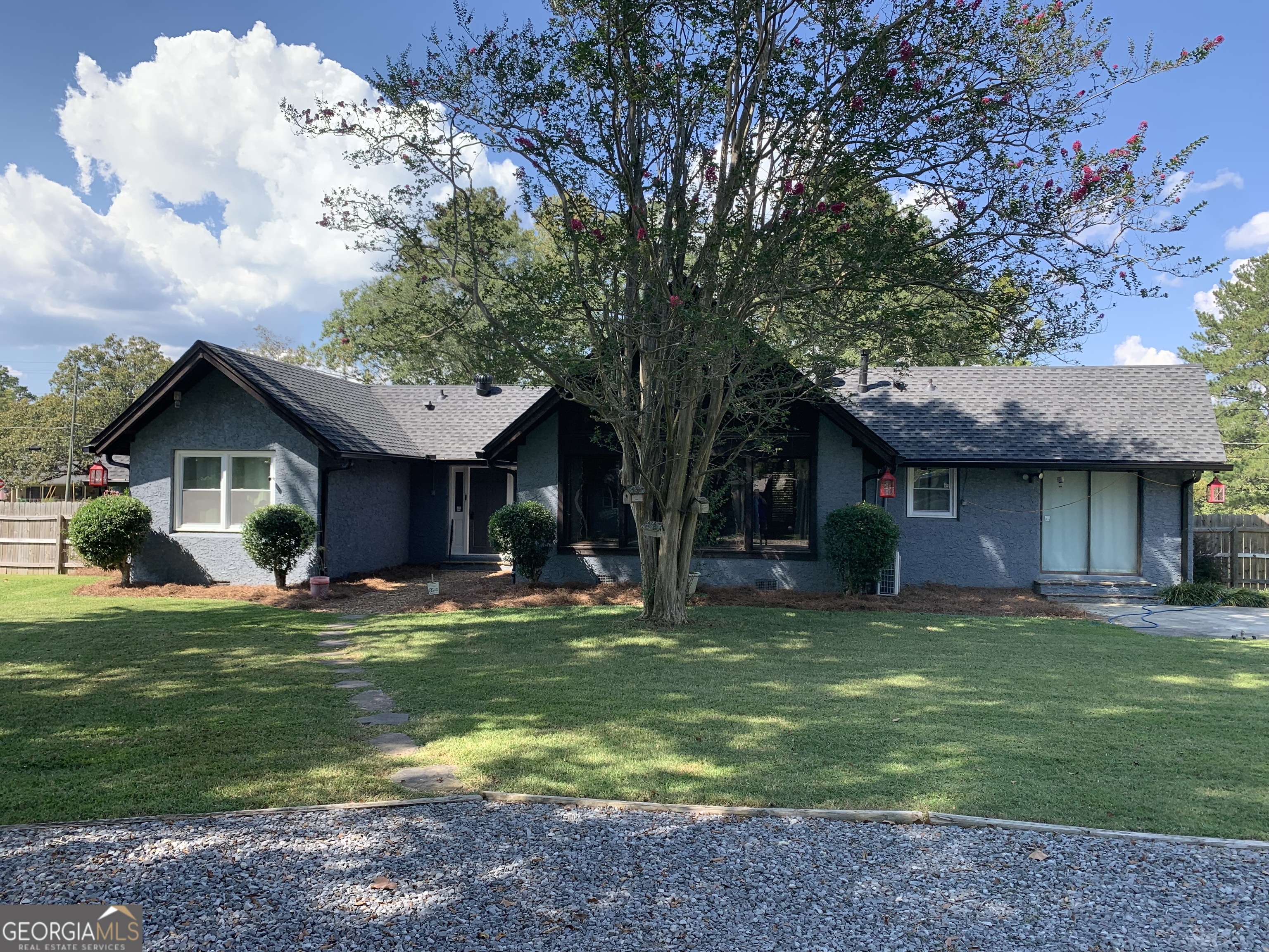 a front view of a house with a garden and trees