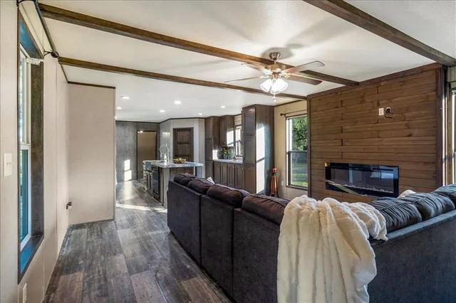 a living room with furniture kitchen view and a wooden floor