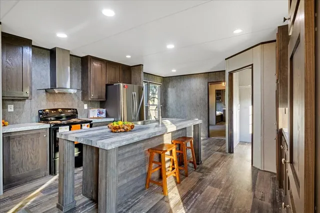 a kitchen with stainless steel appliances granite countertop a refrigerator a stove and a sink