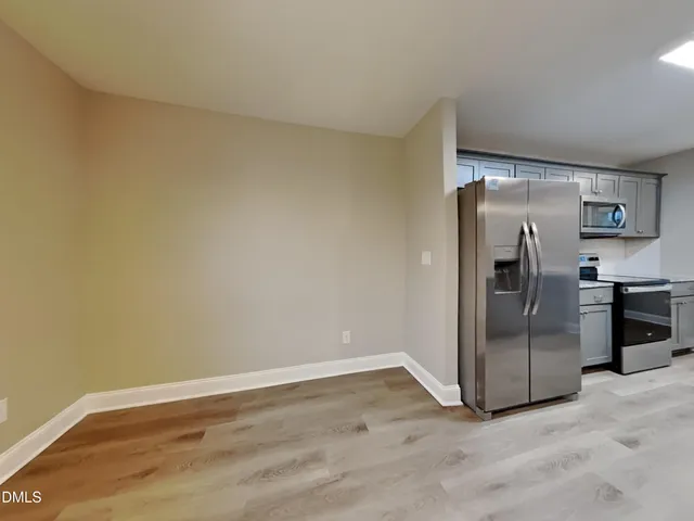 a view of a refrigerator in kitchen and an empty room