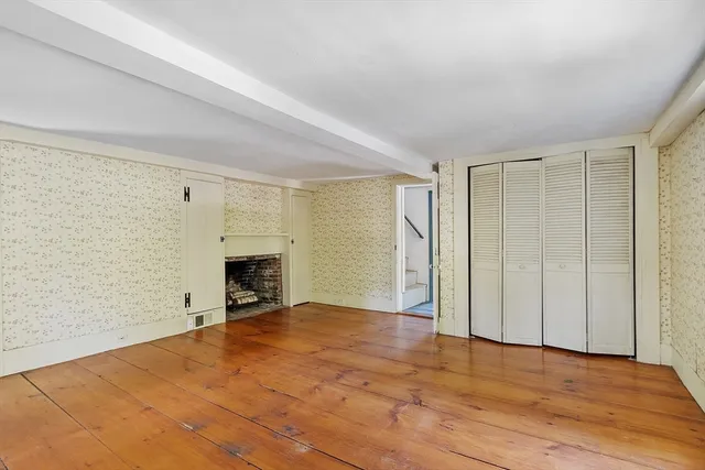a view of empty room with a fireplace and wooden floor