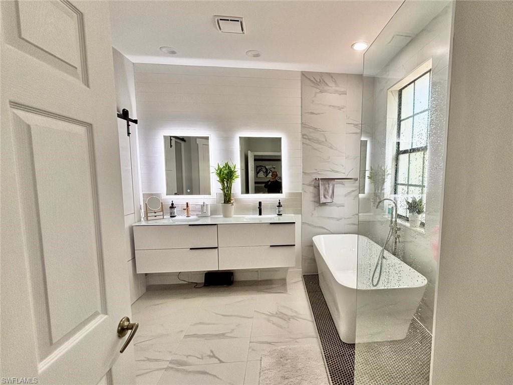 14908 Summit Pl Circle, Unit 26 Naples, FL 34119 - Photo 22 of 26 a bathroom with a tub sink and mirror
