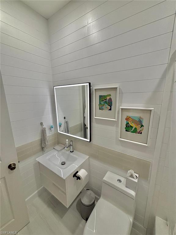 14908 Summit Pl Circle, Unit 26 Naples, FL 34119 - Photo 24 of 26 a bathroom with a toilet sink and mirror
