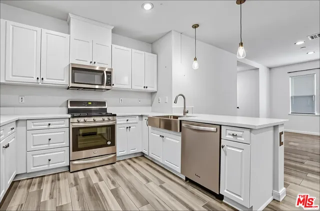 a kitchen with white cabinets stainless steel appliances and sink
