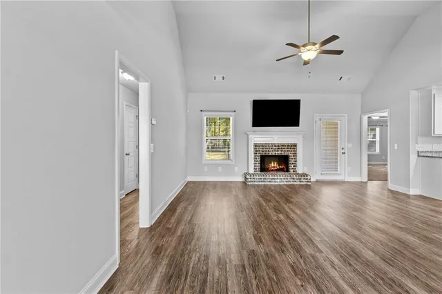 an empty room with wooden floor fireplace and windows