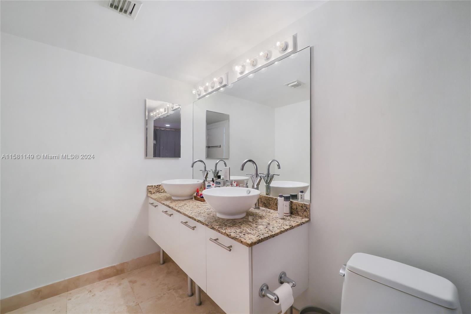 41 Southeast 5th Street, Unit 304 Miami, FL 33131 - Photo 14 of 16 a bathroom with a granite countertop sink a toilet and a mirror