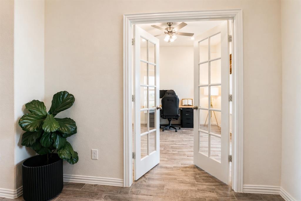 1530 County Road 200 Valley View, TX 76272 - Photo 15 of 34 French doors with clear glass panes open into a room featuring wood-finish flooring, a ceiling fan with light fixture, and neutral-toned walls