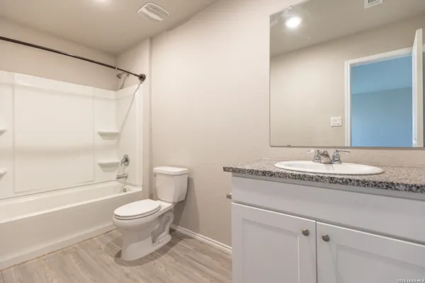 a bathroom with a granite countertop sink toilet a mirror and shower