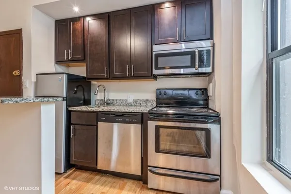 a kitchen with granite countertop cabinets stainless steel appliances and wooden floor