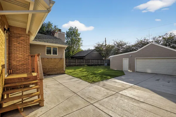 a view of backyard of house with wooden fence
