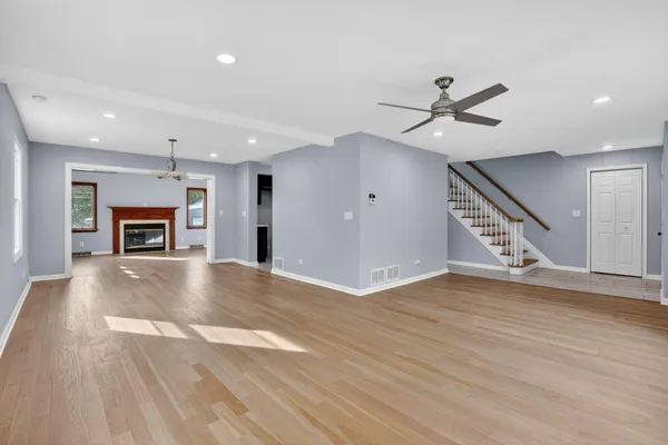 a view of an empty room with fire place and a ceiling fan
