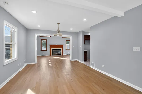 an empty room with wooden floor fireplace and windows
