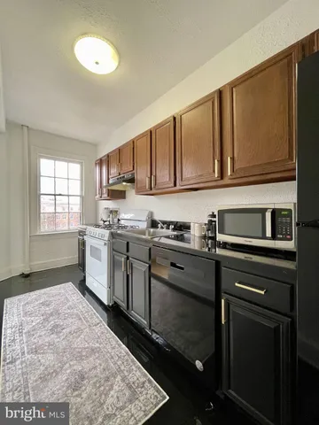 a kitchen with granite countertop a sink cabinets stainless steel appliances and a window