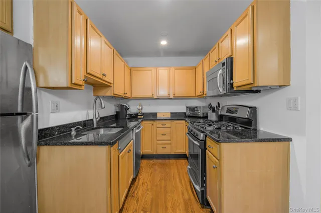a kitchen with stainless steel appliances granite countertop a stove a sink a refrigerator and white cabinets