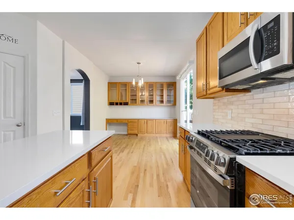 a view of an empty room with a window and a kitchen