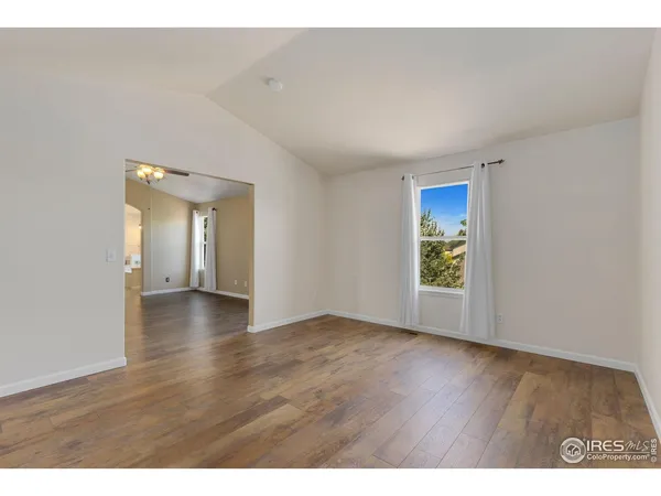 a view of an empty room with window and wooden floor