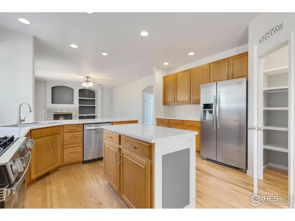 a kitchen with stainless steel appliances granite countertop wooden cabinets a stove top oven a sink and dishwasher with wooden floor