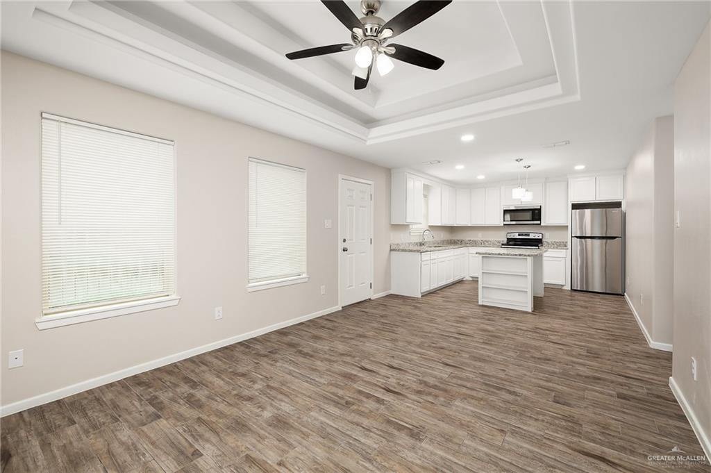 1305 Alta Vista Drive, Unit 4 Weslaco, TX 78596 - Photo 13 of 13 Kitchen featuring open floor plan, a raised ceiling, stainless steel appliances, a kitchen island, and white cabinets