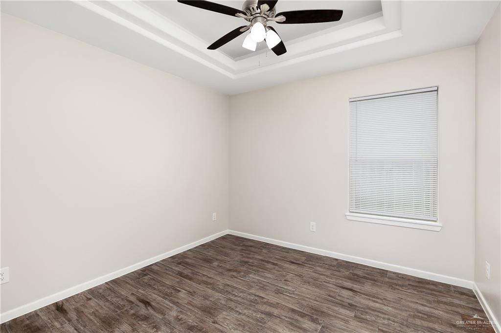 1305 Alta Vista Drive, Unit 4 Weslaco, TX 78596 - Photo 7 of 13 Empty room featuring dark wood-style flooring, a raised ceiling, and ceiling fan