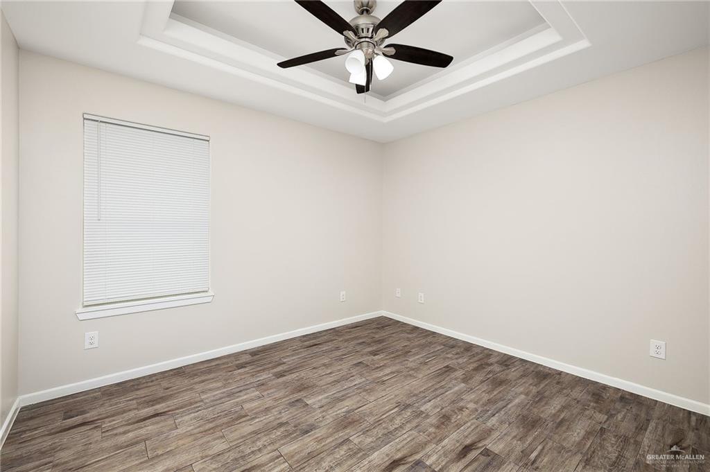 1305 Alta Vista Drive, Unit 4 Weslaco, TX 78596 - Photo 9 of 13 Unfurnished room featuring a raised ceiling, wood finished floors, and ceiling fan