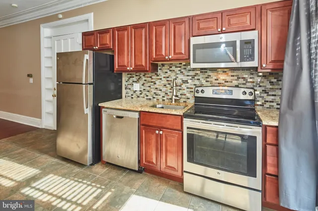 a kitchen with granite countertop a refrigerator stove and microwave